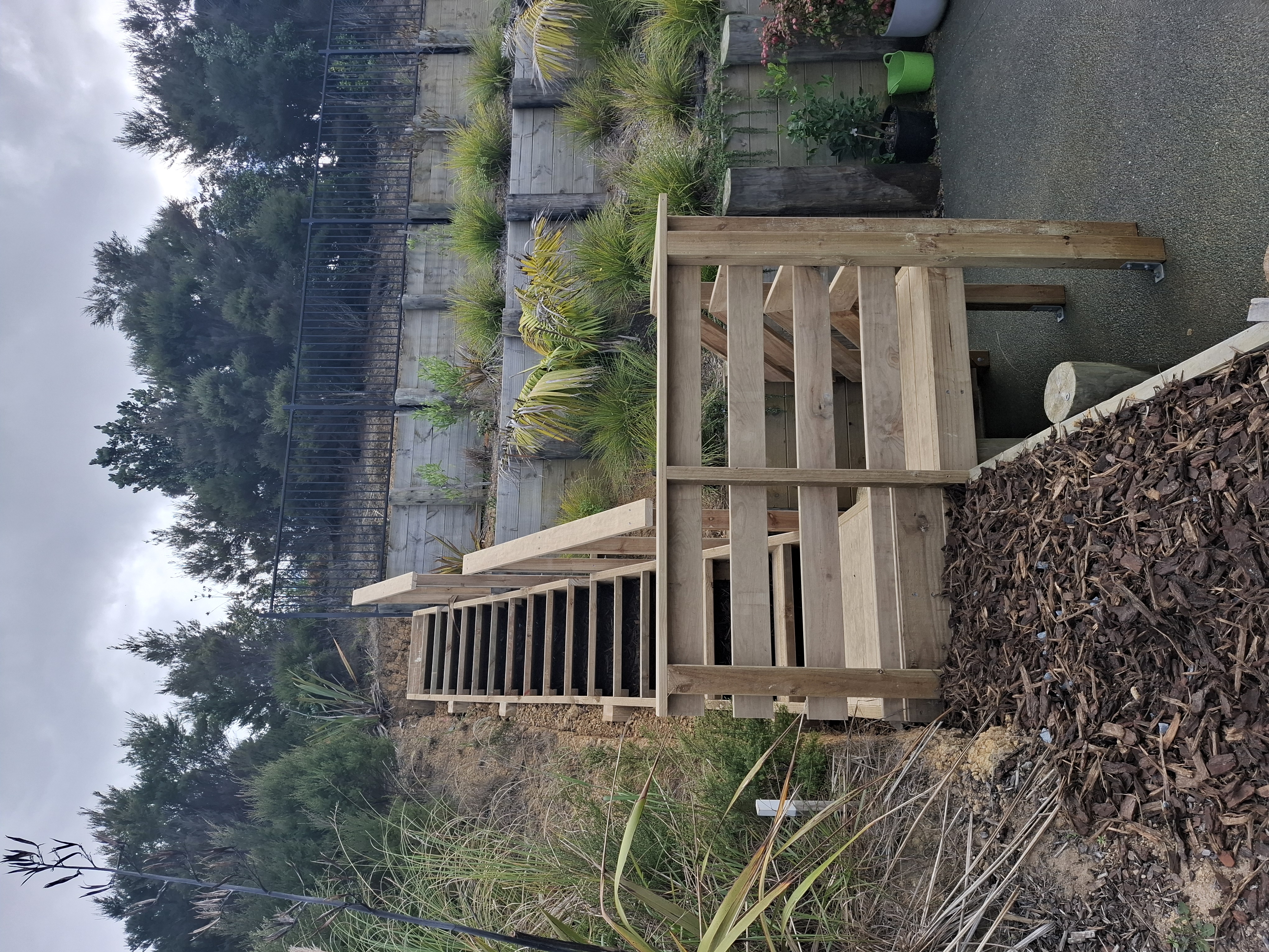 Designed and built by our team, this custom outdoor stairway provides safe, practical access through the client's tiered gardens. Despite the steep terrain and challenging site access, the project was completed with precision to create a durable and attractive solution. - After