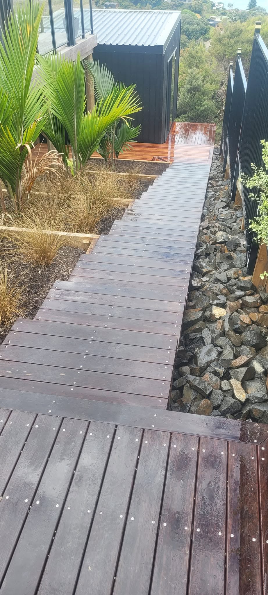 Our team built these custom hardwood stairs to provide safe, durable access to the new sleepout. Designed to suit the challenging site, they complement the home's style while creating a practical and attractive entrance. - After
